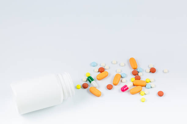 istock Flat lay composition with bunch of different colorful pills scattered on table from popped plastic bottle. Pile of opened medication on white paper textured background. Close up, copy space for text 1334280801
