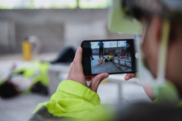 smartphone disparando sobre accidentes e inconsciente de trabajador en el lugar de trabajo en el área de obra mientras tiene el equipo de primeros auxilios de asistencia médica con equipo. - dropped call fotografías e imágenes de stock