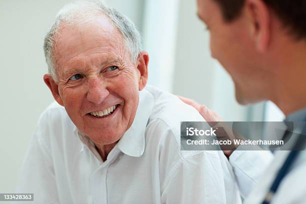 Masculino Doctor Hablando Con Su Paciente Foto de stock y más banco de imágenes de Paciente - Paciente, Doctor, Tercera edad