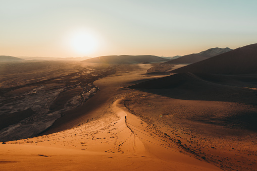 Hombre viajero disfrutar deimeetsng la puesta de sol escénica en las dunas de arena en el desierto de Namib photo