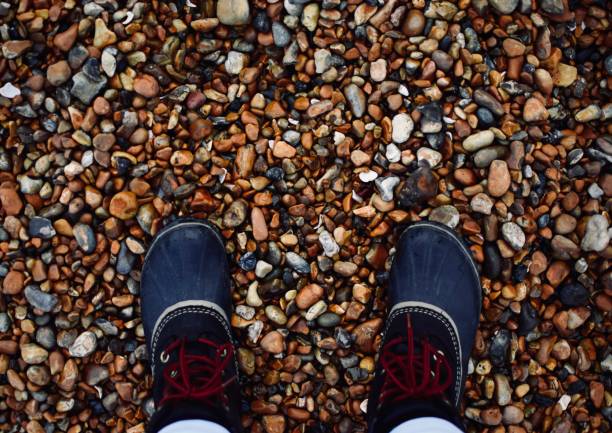 Point-of-view looking over rubber boots on a rocky beach - Brighton, UK