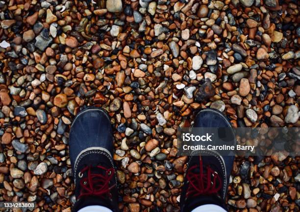Pointofview Looking Over Rubber Boots On A Rocky Beach Brighton Uk Stock Photo - Download Image Now
