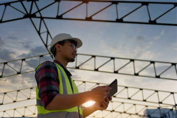 istock Engineering Consulting People on construction site holding tablet in his hand. Management in business workflow and Building inspector with BIM technology in construction project while sunset. 1334283809