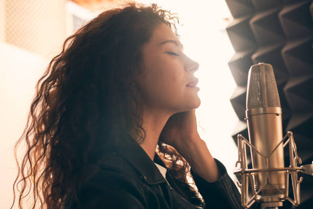 Pretty female singer recording in music studio stock photo