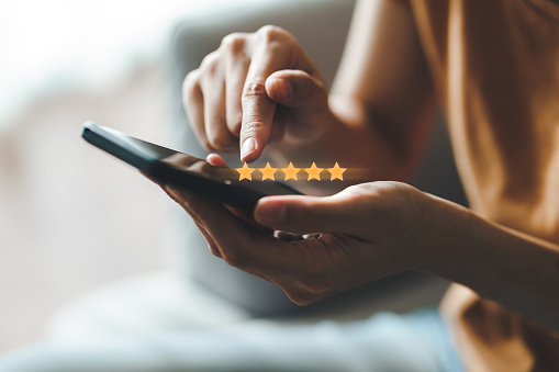 Close up of woman customer giving a five star rating on smartphone. Review, Service rating, satisfaction, Customer service experience and satisfaction survey concept.