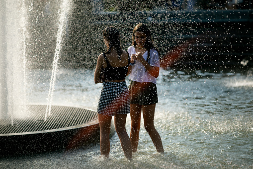 New York City, USA - July 27, 2019:  Two women cooling down in the fountain on a hot summer day at Washington Square Park.