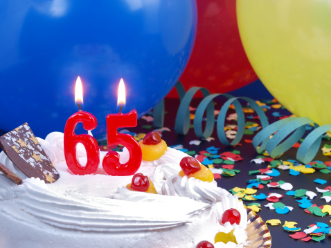 65th. Anniversary / Birthday cake in a Party background with balloons and party strings.