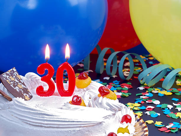 Balloons, confetti, cake and candles for 30th birthday stock photo