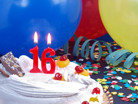 16th. Anniversary / Birthday cake in a Party background with balloons and party strings.