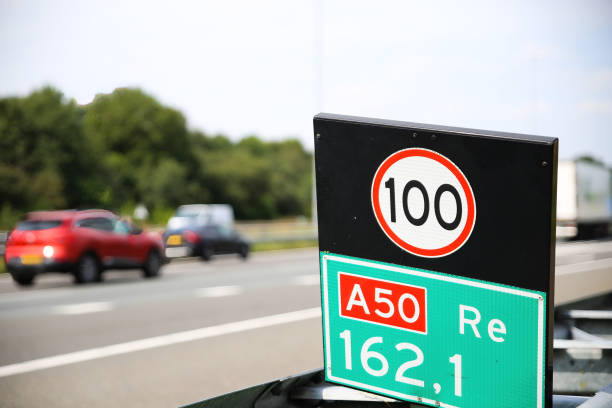 Closeup of 100 speed limit sign at dutch highway, blurred cars background - Netherlands Closeup of 100 speed limit sign at dutch highway, blurred cars background - Netherlands (focus on sign) 100 mph stock pictures, royalty-free photos & images