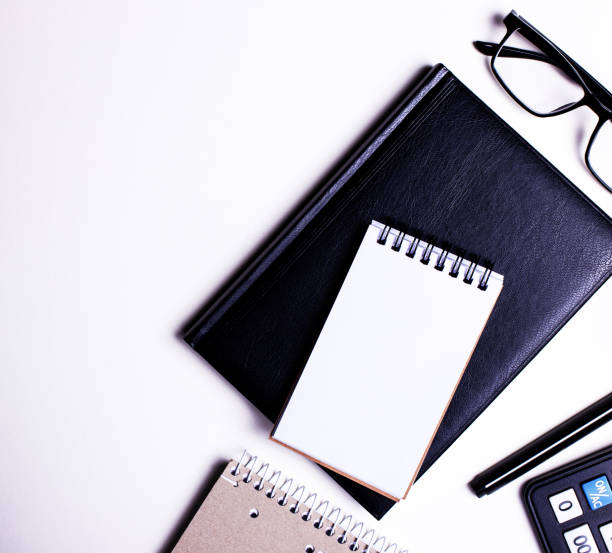 istock On a white table are a calculator, a black pen, a notebook and a flower in a pot. Top view close up, place for text. 1334296769