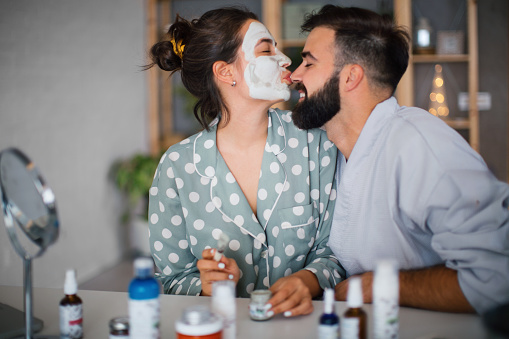 Young couple applying a facial mask to their faces in their evening routine.