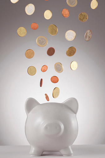 Piggy Bank with falling euro cents in front of a blue background