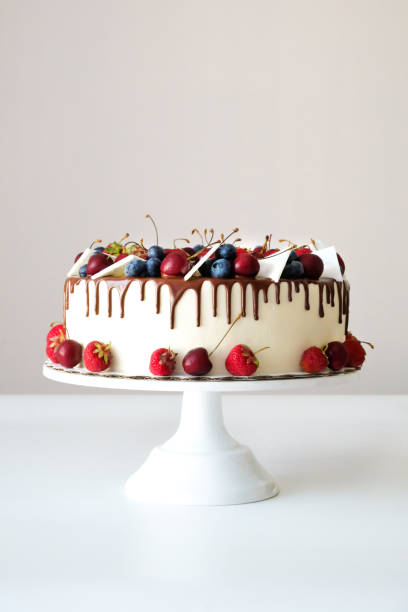 istock Birthday cake in chocolate with strawberries, blueberries and cherry on white background. Picture for a menu or a confectionery catalog. 1334302329