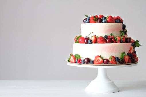 Stock photo showing elevated view of slices of chocolate and cherry cake, Black Forest gateau, red velvet, rainbow cake, coffee and marbled chocolate gateau displayed on a circle of greaseproof parchment paper against a marble effect background.