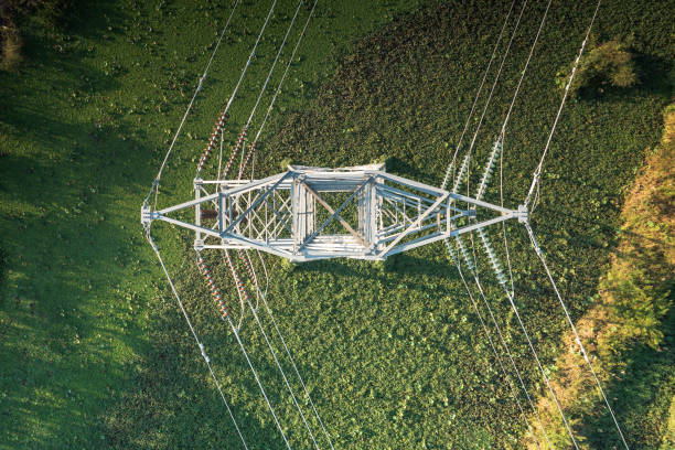 Transmission tower or electricity pylon in aerial view or top view for carry high-voltage transmission lines. Transmission tower or electricity pylon in aerial view or top view. That substation, utility or infrastructure for network of electrical grids system consist of high tension wire, cable, overhead power line, tall steel structure. Include glass field background. For carry high-voltage transmission lines to distribution, supply electric current or energy for city, urban. power mast stock pictures, royalty-free photos & images