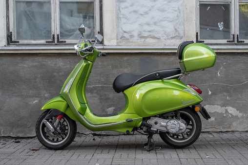 Tallinn, Estonia - August 06 2021: Green Vespa scooter parked on the city street in Tallinn Old Town.