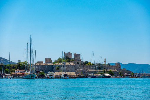 Bodrum, Turkey - July 26, 2021: Fisherman boats and yachts in Bodrum harbour. Bodrum Castle is  background