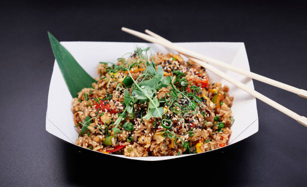 istock Chinese wok fried rice with vegetables on black background 1334304531