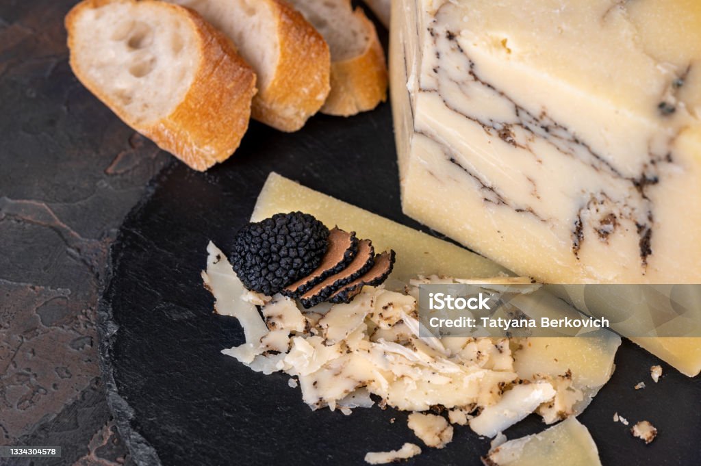 Italian hard cheese Pecorino romano with black truffle Italian hard cheese Pecorino romano with black truffle on dark background Chocolate Truffle Stock Photo