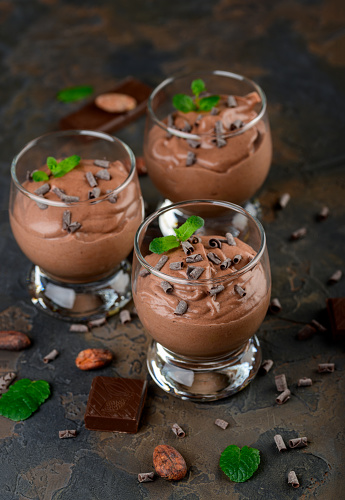 Vegan chocolate mousse with mint, bar of chocolate and cocoa beans on a dark background. Copy space