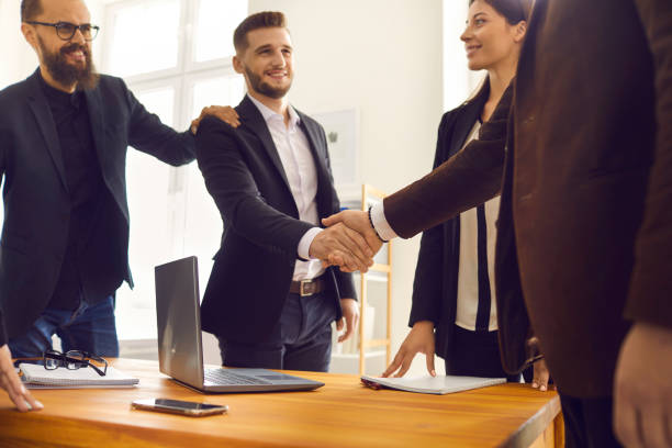 istock Smiling young business partners shaking hands after successful negotiations in office 1334305420