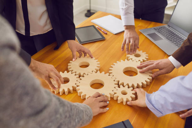 istock Company workers joining cogwheels as metaphor for teamwork, business system and working solutions 1334305421