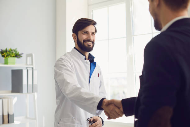 istock Handshake. Practicing doctor and patient shaking hands smiling at the clinic. 1334305699