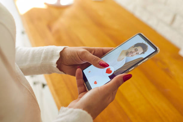Single woman holding mobile and giving like to man's profile picture on dating app stock photo