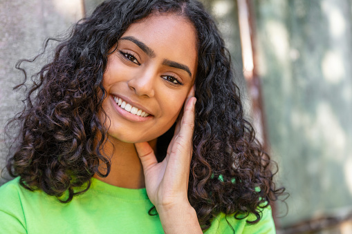 Outdoor portrait of beautiful happy mixed race African American girl teenager female young woman thinking and smiling with perfect teeth