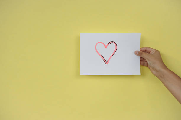 istock Heart held with one hand on yellow background 1334308294