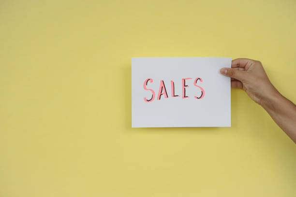 istock Sale poster held with one hand on yellow background 1334308321
