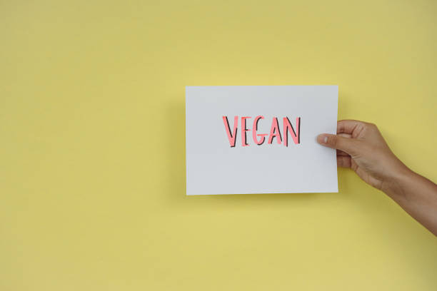 istock Vegan poster held with one hand on yellow background 1334308426