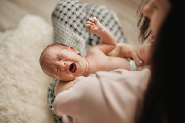 crying hungry newborn in the arms of his mother stock photo