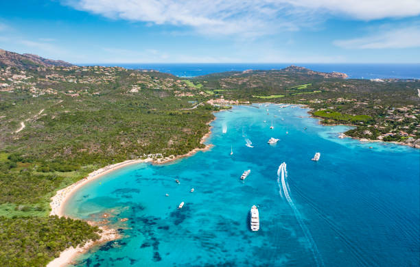 View from above, stunning aerial view of the Cala di volpe bay with a green coastline, white sand beaches and luxury yachts sailing on a turquoise water. Liscia Ruja, Costa Smeralda, Sardinia, Italy. View from above, stunning aerial view of the Cala di volpe bay with a green coastline, white sand beaches and luxury yachts sailing on a turquoise water. Liscia Ruja, Costa Smeralda, Sardinia, Italy. Cala Di Volpe stock pictures, royalty-free photos & images