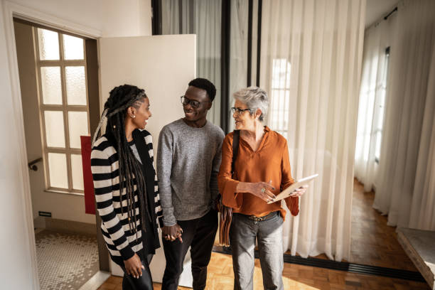 Real estate agent showing apartment to young couple Real estate agent showing apartment to young couple estate agent stock pictures, royalty-free photos & images