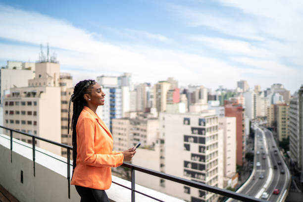 istock Young woman contemplating and using smartphone in a rooftop 1334323351