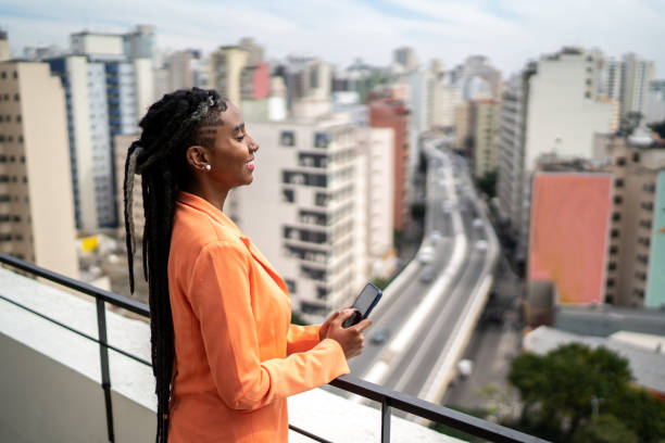 istock Young woman contemplating and using smartphone in a rooftop 1334323379