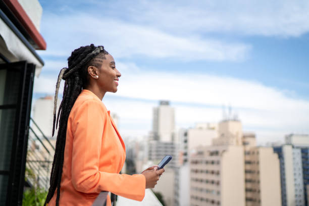 istock Young woman contemplating and using smartphone in a rooftop 1334323385