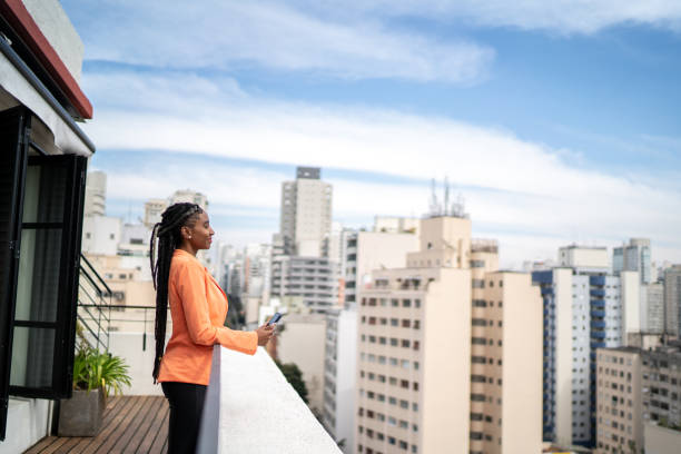 istock Young woman contemplating and using smartphone in a rooftop 1334323400