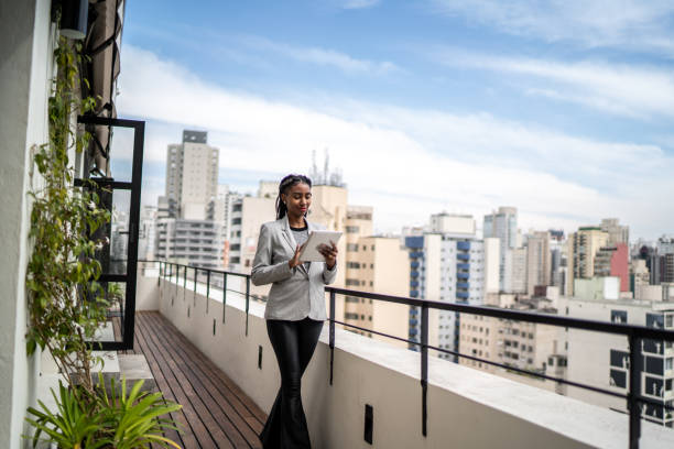 Young businesswoman using digital tablet on apartment's balcony
