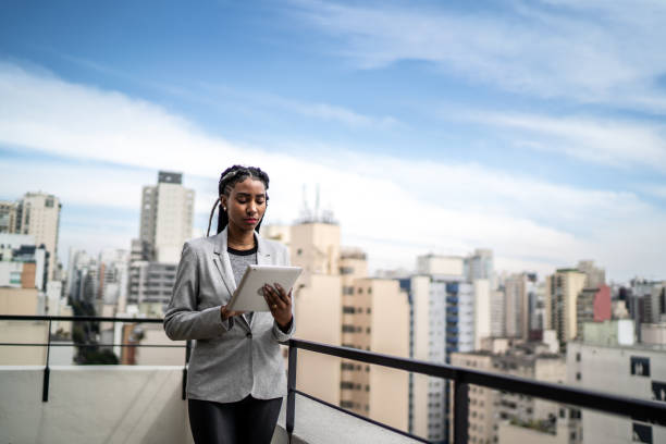 istock Young businesswoman using digital tablet on apartment's balcony 1334323943
