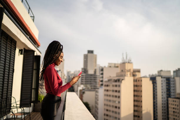 istock Young woman using smartphone on apartment's balcony 1334325267
