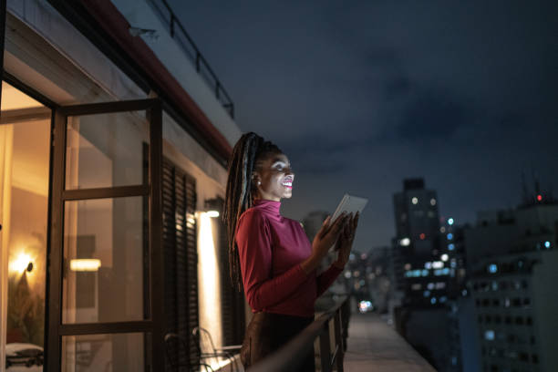 istock Happy young woman contemplating while using digital tablet on apartment's balcony 1334326999