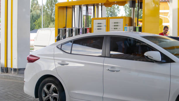 白い車が給油中です。ガソリンスタンドに駐車している車に給油。ガソリンポンプで車に燃料を補給します。石油・ガスエネルギー。ウクライナ, キエフ -15 8月, 2021 - gasoline car buying fuel pump ストックフォトと画像