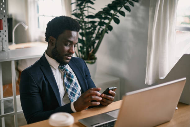 istock Black employee chatting on smartphone against laptop in office 1334328244