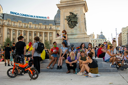 14.08.2021 Romania - Bucharest. Group of people settling down for conversations around the statue at the University while attending the lgbt, pride parade.