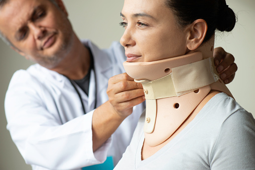 Doctor removing the neck brace from woman. Neck protector.