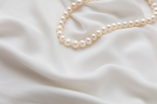 Close up of a white pearl beaded purse, beads and other accessories
