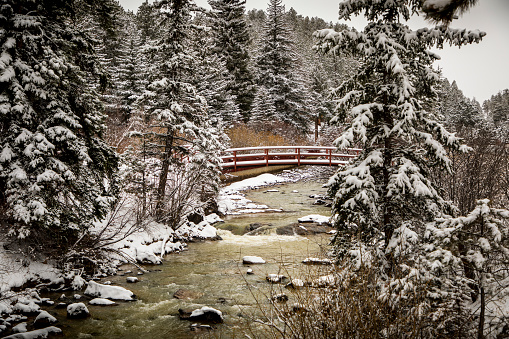 Snow falls on a bridge crossing the North Fork Platte River in Bailey, Colorado on a cold winter day.
